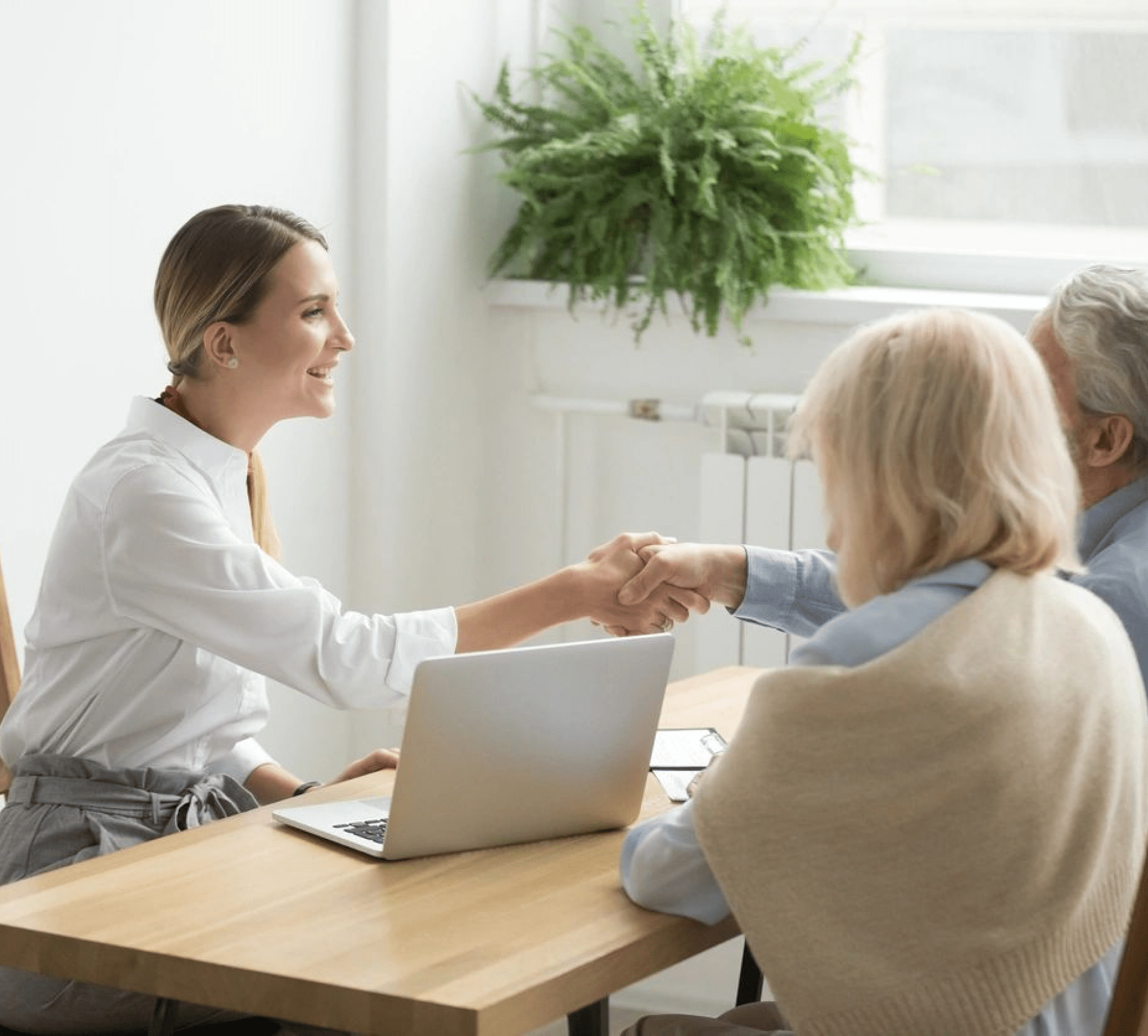 A woman shaking hands with another person at a table.