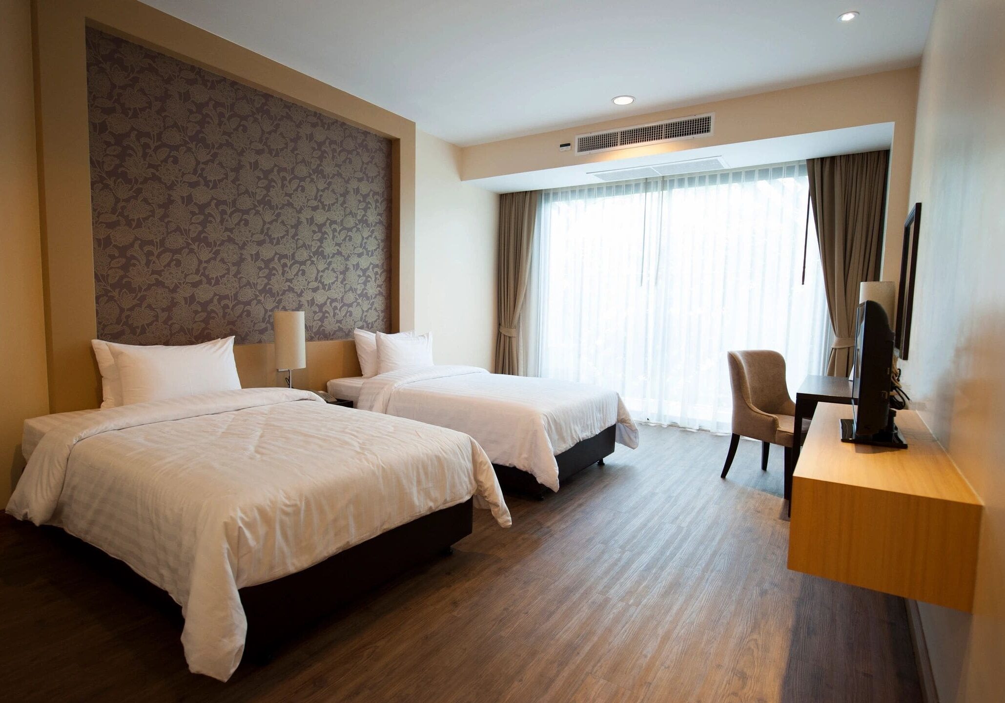 A hotel room with two beds and a desk.