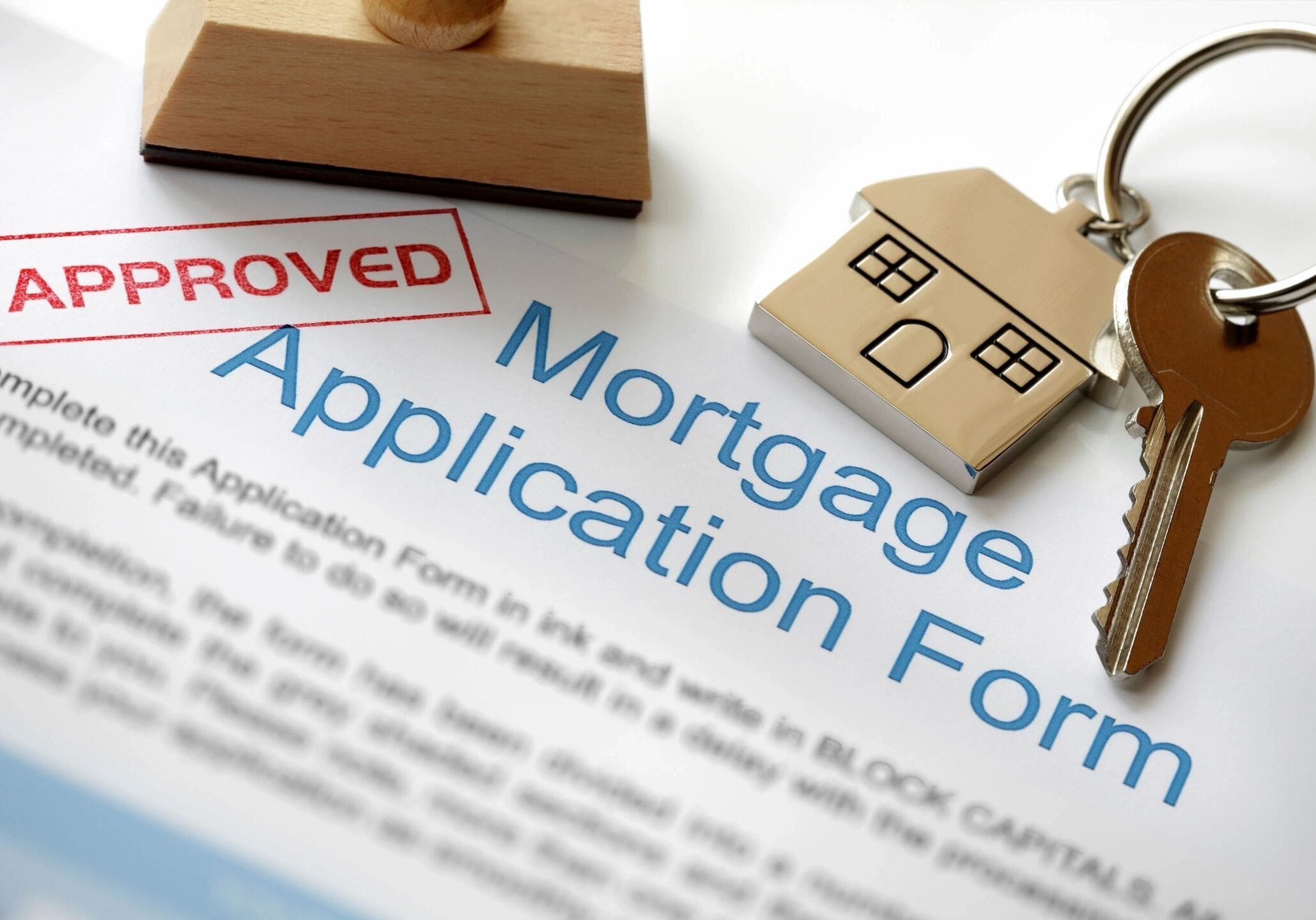 A mortgage application form with a stamp and house key.