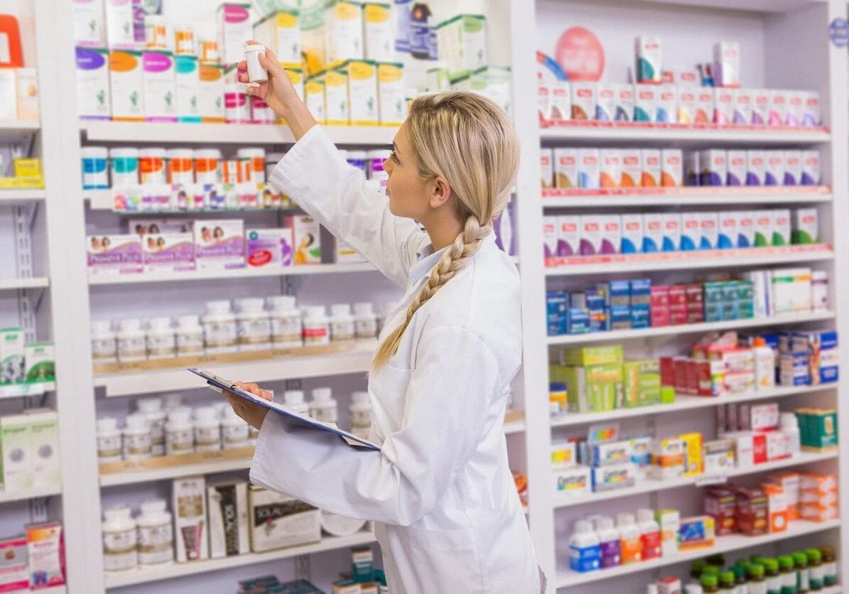 A woman in white lab coat holding a tablet.