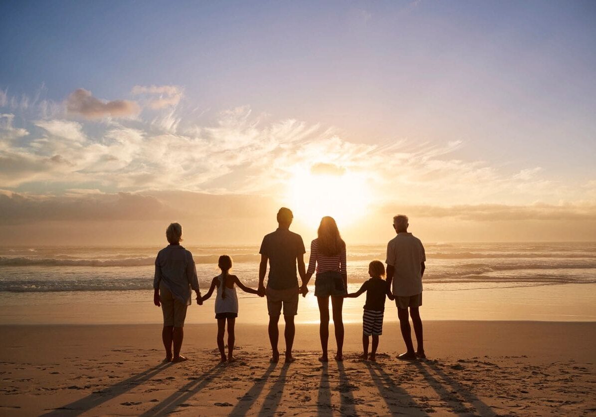 A family standing on the beach holding hands.